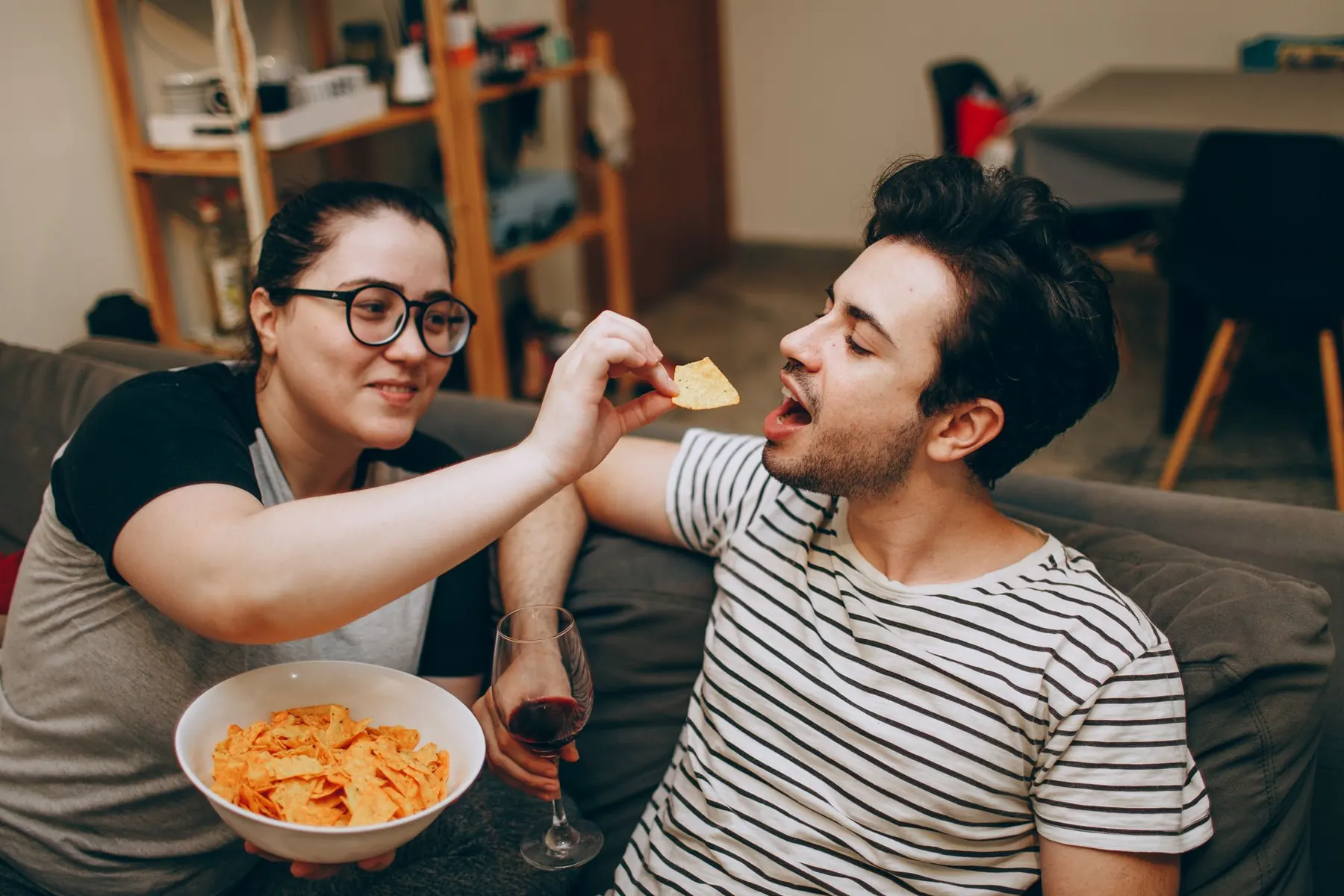 Two friends sharing a bowl of chips on the couch