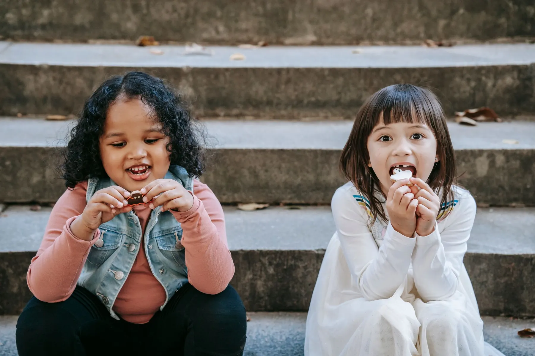 Two girls sitting on steps enjoying a snack
